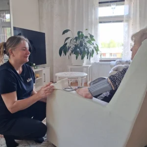 Alina-hoitaja mittaamassa ikääntyneen asiakkaan verenpainetta Pähkinärinteessä.
